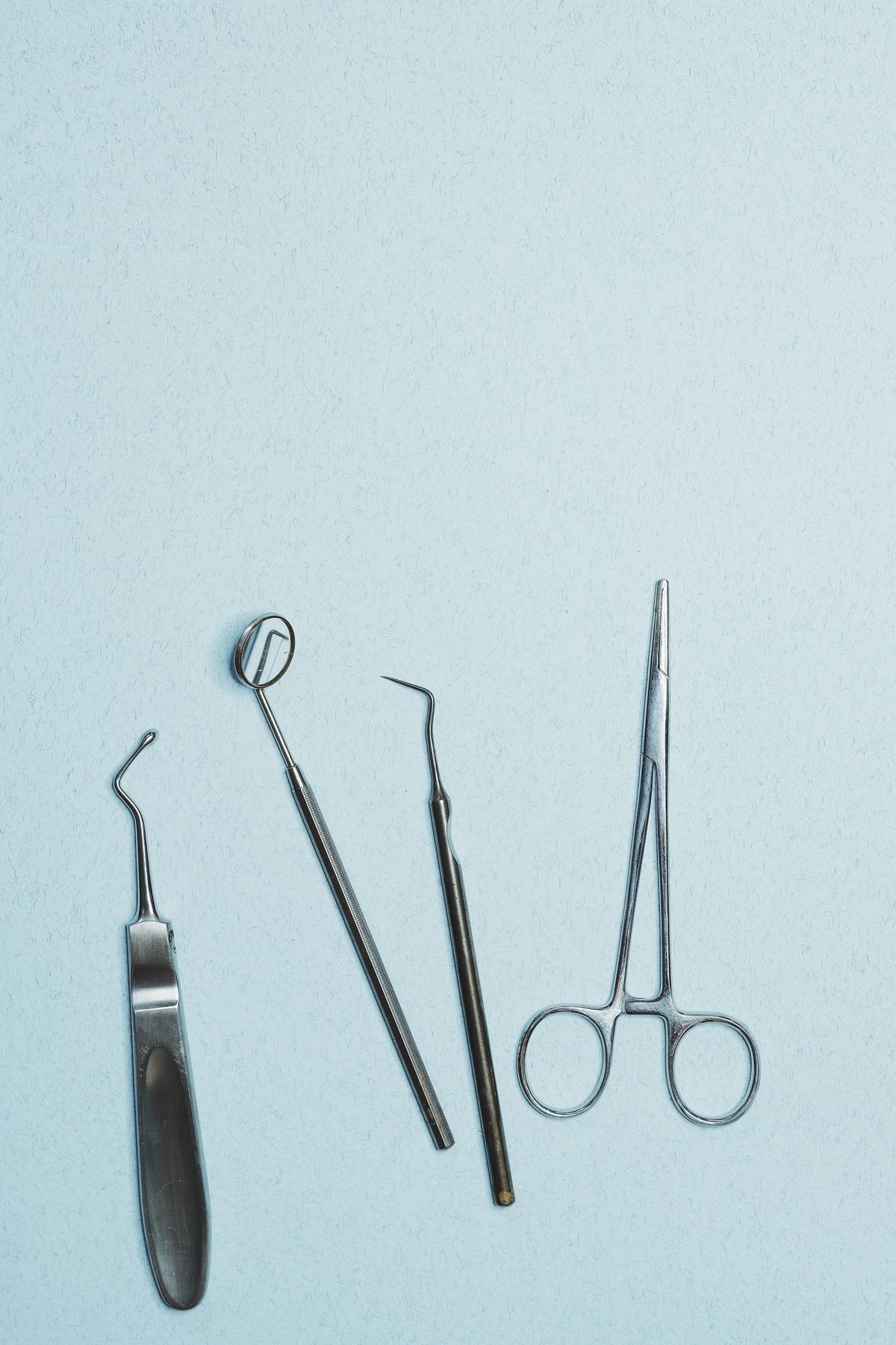 Instruments dentaires en inox sur fond bleu clair