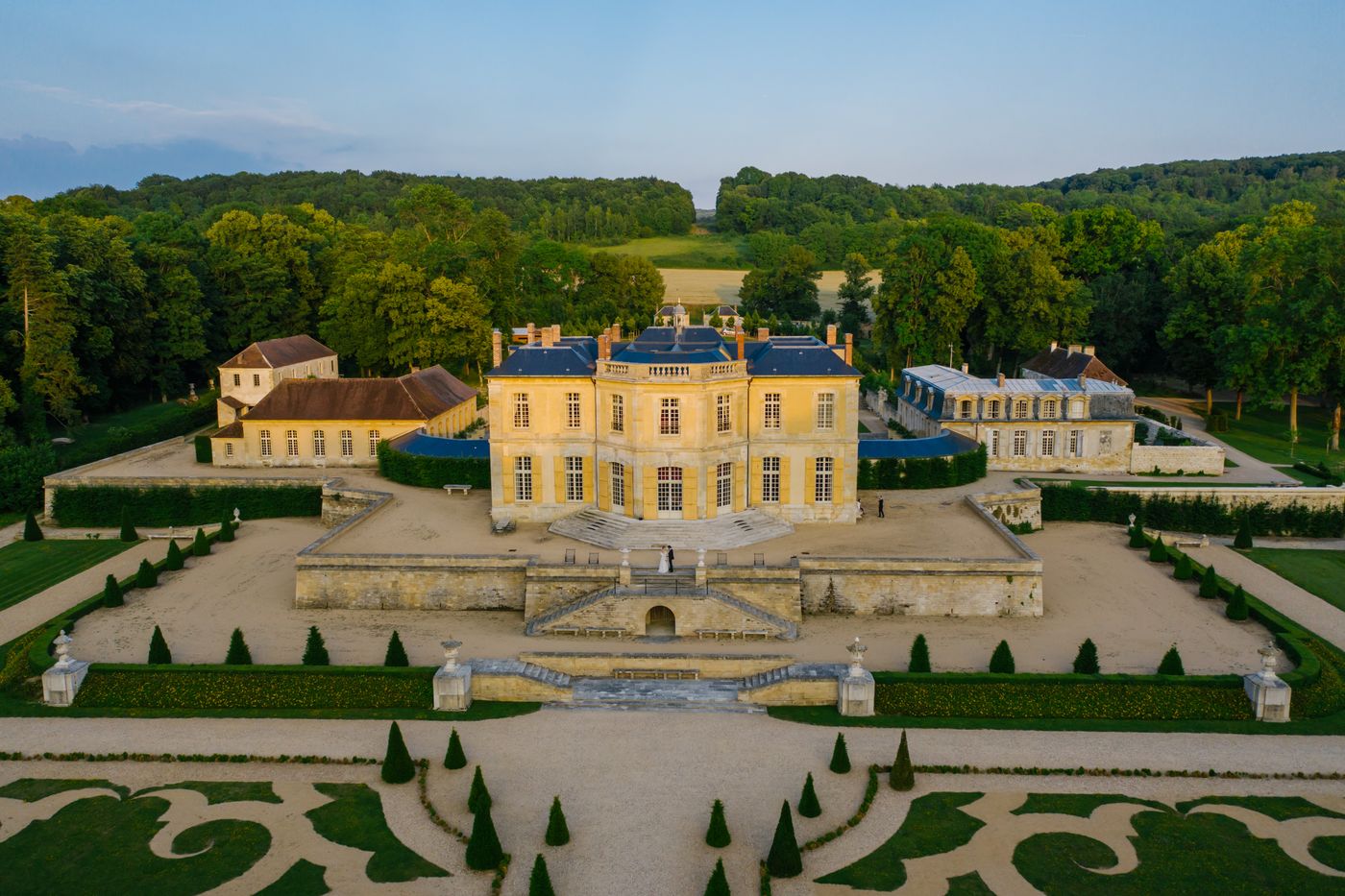 Vue aérienne du château et de ses jardins à la française à l'heure dorée