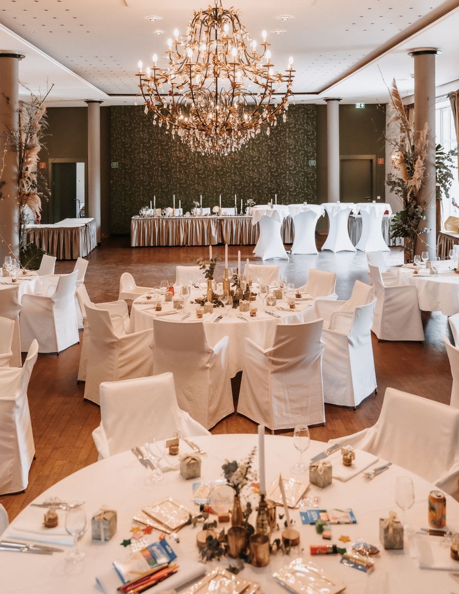 Salle de réception du château : lustre, tables rondes dressées de blanc