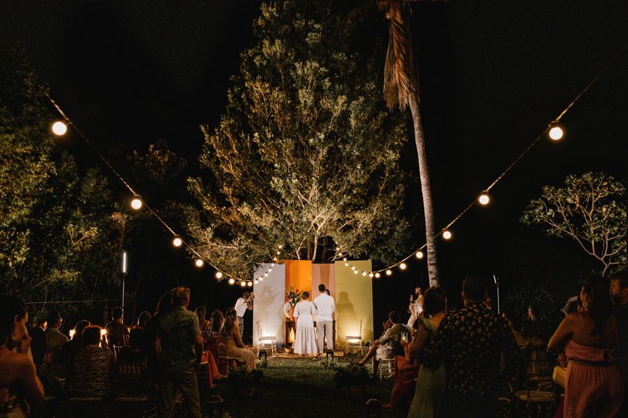 Soirée de mariage en plein air à la nuit tombée, sous des guirlandes lumineuses