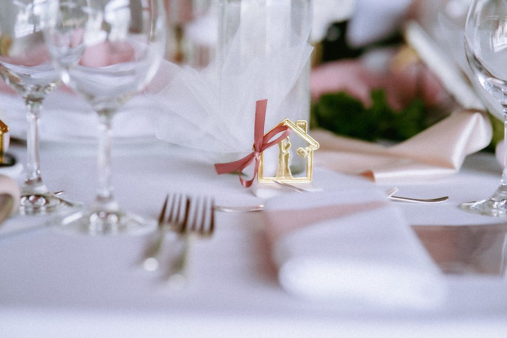 Détail de table de mariage : verres, fourchettes et cadeau d'invité doré