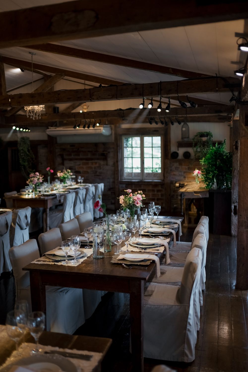 Réception dans la grange : poutres en bois, longues tables fleuries