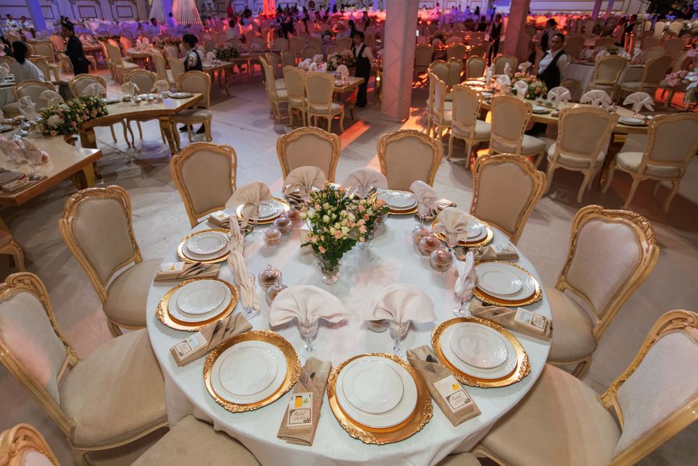 Table ronde dressée avec assiettes dorées et fleurs pastel