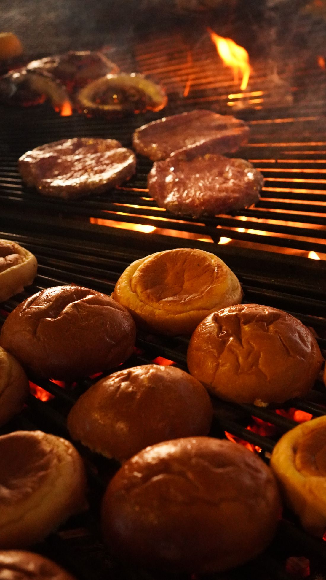 Steaks et pains briochés qui dorent sur la grille, au-dessus de la braise
