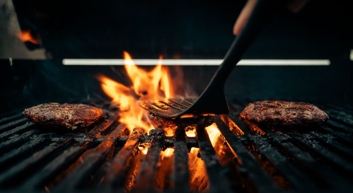 Spatule sur la grille, flammes du feu de bois dans la nuit