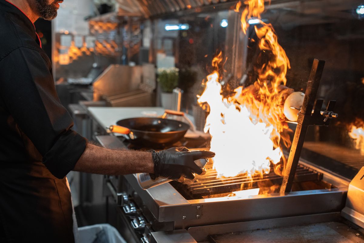 Cuisinier saisissant la viande à la flamme sur le grill du camion